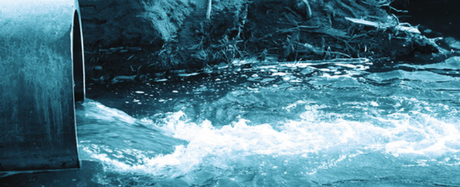 blue water pours out of a metal pipe into a larger body of water